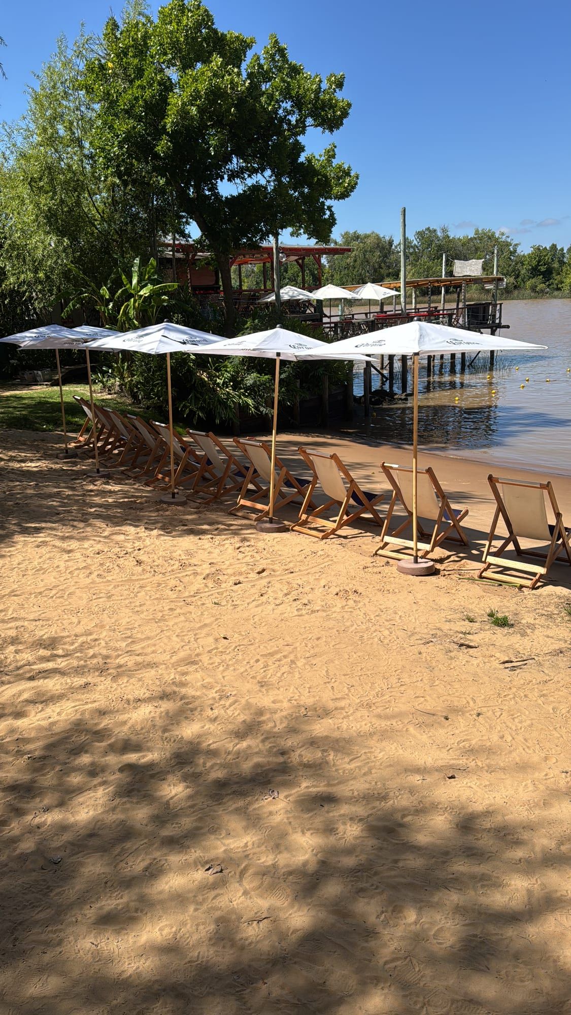 La playa con sombrillas y reposeras frente al Río San Antonio.
